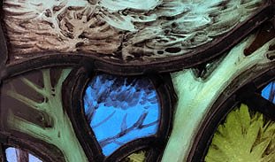 a stained glass detail of a green tree with a blue sky peeking through