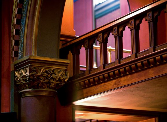 Church column with stone railing, light revealing hues of red, purple, and ochre