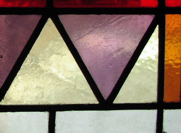 Stained glass in purple, pale green, and red-brown, in a geometric arrangement (mostly triangles)