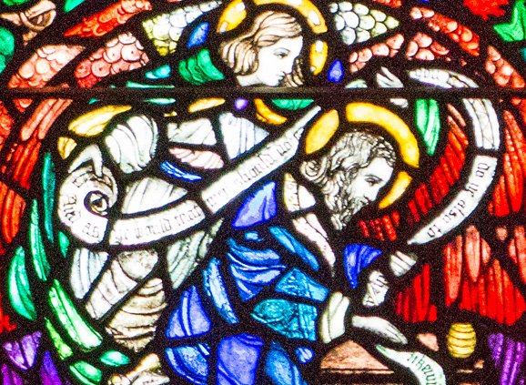 red, green, white, and blue stained glass depicting two figures: a man and an angel with a scroll
