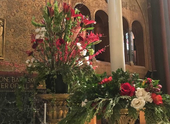 Red flowers and greenery in vases on Trinity's altar