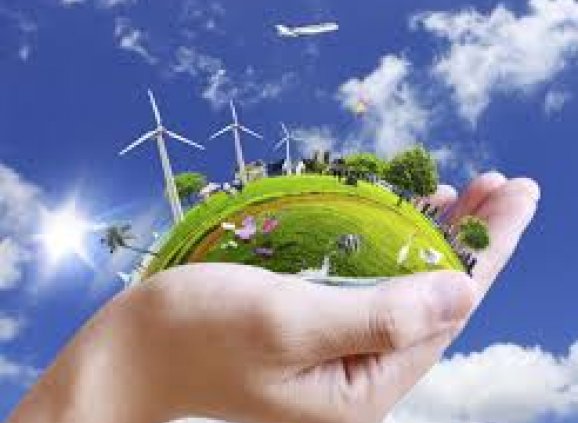 a hand holding a green earth with wind turbines.
