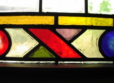 Stained glass in red, green, purple, yellow and blue in a geometric arrangement.