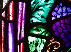 purple, green, and red stained glass depict grapes and leaves and folds of fabric