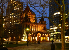 the exterior of Trinity Church glows at dusk with Christmas lights and a Christmas tree