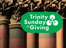 Trinity's rounded, heavy columns painted maroon and green are capped with carved leaves. The 'Trinity Sunday of Giving' logo, in a kelly green, is overlaid on top of the columns image